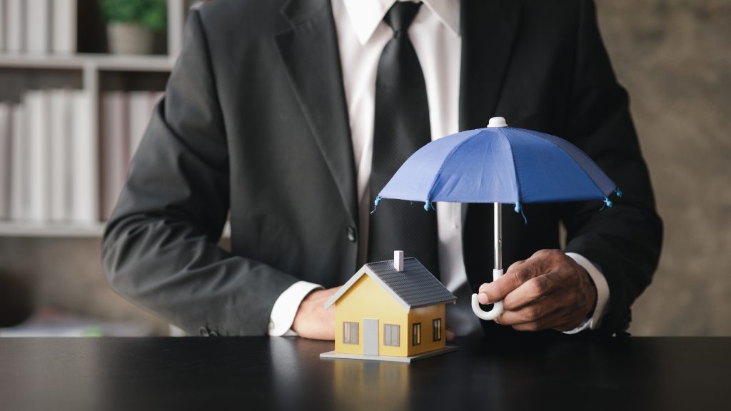 Individuals holding small umbrellas and model homes, housing ins